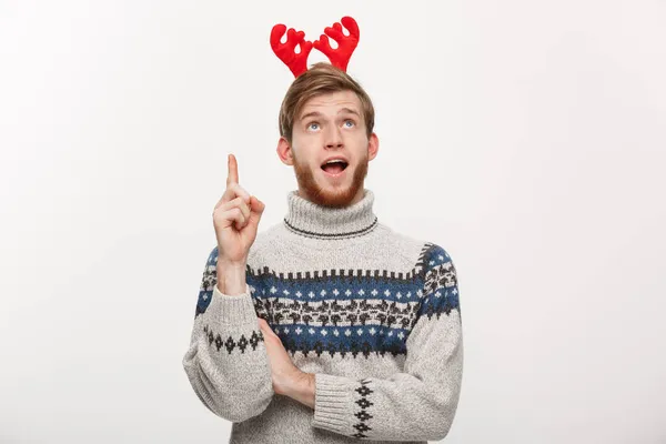 Holiday Concept - Νεαρός γενειοφόρος με πουλόβερ απολαμβάνει να παίζει και να δείχνει το δάχτυλο προς τα πάνω. — Φωτογραφία Αρχείου