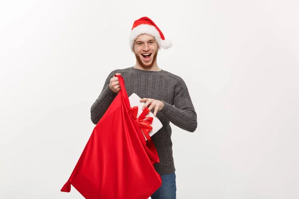 Kerst Concept - jonge gelukkig baard man prikkelen met grote heden in santa zak. — Stockfoto