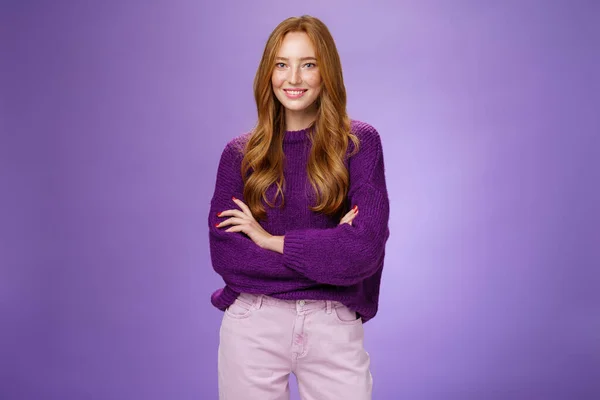 Портрет довольно молодой и счастливой 20-летней рыжей девушки в фиолетовом свитере, держащейся за руки, широко улыбающейся, чувствующей себя уверенной в себе, продвигающей проект с уверенностью над фиолетовой стеной — стоковое фото