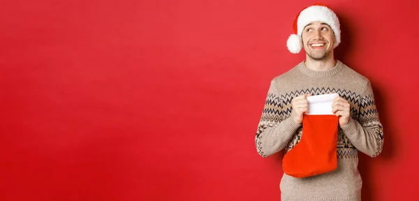 Begreppet vinter semester, nytt år och fest. Bild av överraskad och glad man får gåva från hemliga Santa inne jul strumpa väska, öppen gåva och ser tacksam — Stockfoto