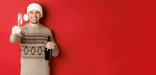 Begreppet vinter semester, nytt år och fest. Porträtt av stilig man i tomte hatt och tröja, hålla champagne, höja glas och säga skål på julfest — Stockfoto