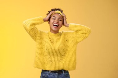 Dost canlısı, mutlu, gülümseyen, beyaz dişli, Afro-Amerikan kadını, harika bir tatil gününde eğleniyor, kafa sallıyor, gülüyor, kameraya bakıyor, eğleniyor, şakalaşıyor, pozitif, sarı arka plan