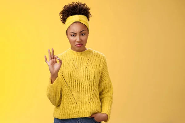 Well not bad. Portrait serious-looking confident arrogant young african-american woman agree effort good show okay ok normal gesture smug approval, standing yellow background impressed