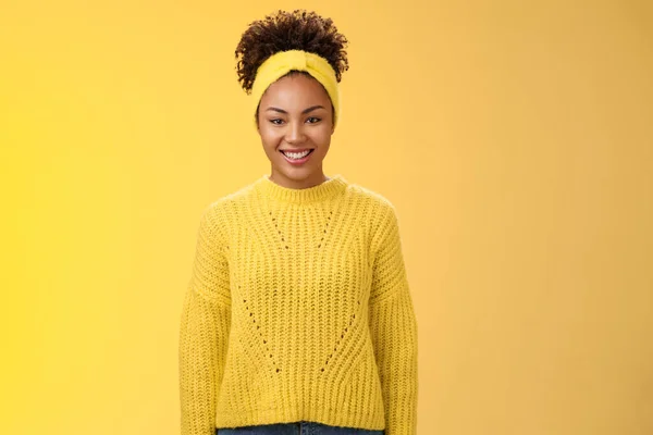 迷人的、友善的、微笑的黑人女孩，卷曲的非洲式发带，兴奋地笑着参加大学活动，帮助站在外向的、充满活力的黄色背景上 — 图库照片