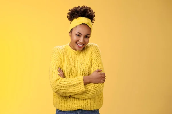 温柔娇嫩娇嫩的年轻非洲裔美国人快乐的女友卷曲发式的发带毛衣拥抱自己欢快微笑的相机感觉柔软舒适，站在黄色背景温暖 — 图库照片