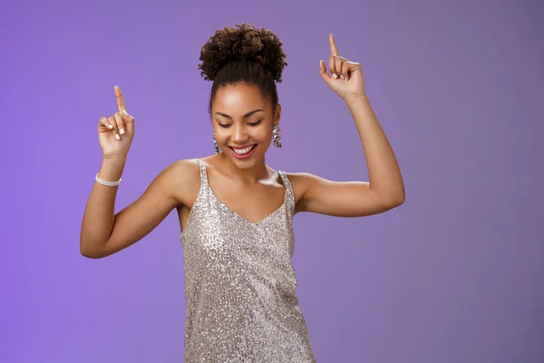 Good-looking carefree african-american girl student have fun prom dancing night club smiling delighted raicing index fingers up joyfully look down, triumphing celebrating good news, blue background
