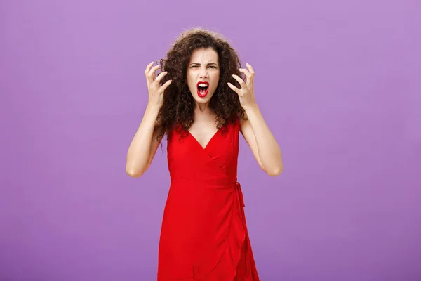 Woman getting annoyed and pissed employees spoiling her perfomance. Portrait of outraged furious female musician in red evening dress raising clenched fists grimacing and yelling angry