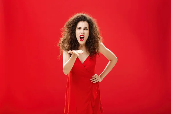 How dare you betray me. Pissed outraged bossy and displeased european adult woman with curly hairstyle in elegant dress bending towards camera with raised palm, complaining blaming and judging — стоковое фото