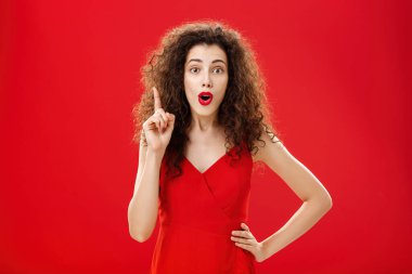 Harika bir fikrim var. Yaratıcı dost canlısı ve zeki beyaz kadın portresi. Şık kırmızı elbiseli, akşam makyajı soluk soluğa. Eureka jestinde işaret parmağını kaldırma önerisi ekliyor.