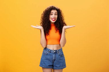 Üzgünüm, tatlım. Kıvırcık saçlı, silkelenmiş silkelenmiş silkelenmiş, elleri yana açılmış aptal Avrupalı bir kadın suçlu gülümsüyor ve turuncu arka planda sorgulanıyor.