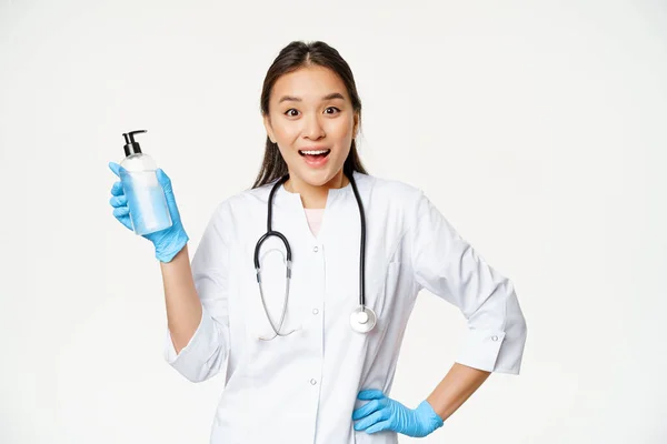 Üniformalı tutkulu bayan doktor, el sabunu, dezenfektan, covid-19 önleme, beyaz arka planda duruyor. — Stok fotoğraf