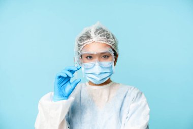 Asyalı kadın doktor portresi yakın çekim, kişisel koruyucu ekipman hemşiresi aşıyı gösteren şırınga, grip aşısı ya da mavi arka plan