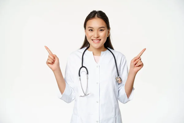 Beyaz cüppeli, gülümseyen profesyonel doktor, parmaklarını yana doğru gösteriyor ve her iki yönde de beyaz arka plana karşı duran iki reklam gösteriyor. — Stok fotoğraf