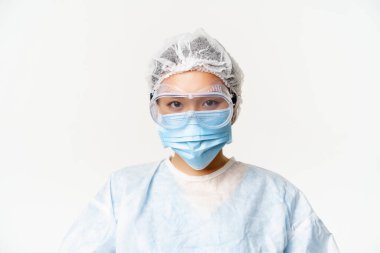 Yüz maskesi ve koruyucu gözlük takan, beyaz arka planda duran Asyalı kadın doktor veya hemşire.