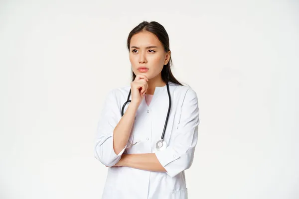 Bild av allvarlig läkare, kvinnlig vårdpersonal tänkande, titta åt sidan med oro, rynka ansikte uttryck, vit bakgrund — Stockfoto
