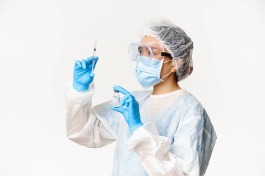 Covid-19, koronavirüs ve aşı kampanyası konsepti. Asyalı hemşire ya da yüz maskeli doktor şırıngayı aşıyla dolduruyor, beyaz arka planda duruyor.