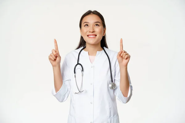 Feliz médico sonriente, mujer asiática médico mirando hacia arriba con expresión de la cara alegre, vistiendo uniforme médico, fondo blanco — Foto de Stock