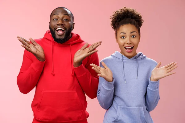 Impressed happy thrilled young pair african man woman relationship clapping palms joyfully surprised wide eyes joyfully greeting friends inviting come in hospitable, standing pink background — Stock Photo, Image