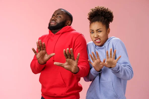 Studio Shot Paar afrikanisch-amerikanische Freunde Frau Mann krampfhaft Ekel Abneigung Gefühl peinlich widerstrebend Schritt zurück heben Handflächen defensive Ablehnung versuchen stinky Produkt, stehend rosa Hintergrund — Stockfoto