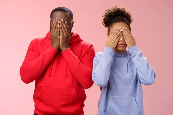 Two african-american man woman standing pink background hide faces close eyes palms tired looking lies upset waiting sign command see, playing hide-n-seek, unwilling spot personal problems — Stock Photo, Image