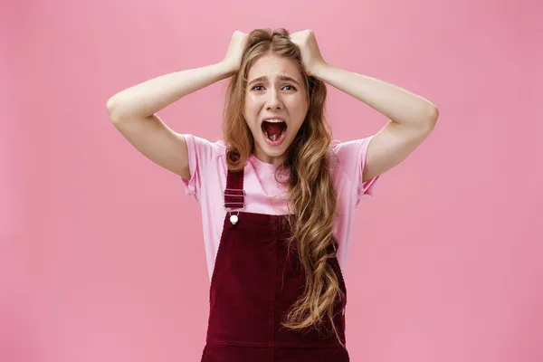 Cintura-up tiro de mulher em pânico gritando e puxando o cabelo para fora da cabeça sorridente sentindo ansiedade de estresse e problemas de pé incomodado e angustiado contra fundo rosa — Fotografia de Stock