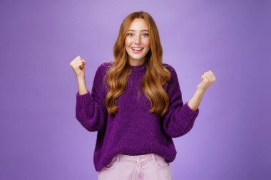 Başarılı bir çaba sarf ettiği için kendiyle gurur duyuyor. Kutlama ve zafer için yumruklarını kaldırıyor. Şaşırmış ve rahatlamış bir şekilde gülümsüyor.