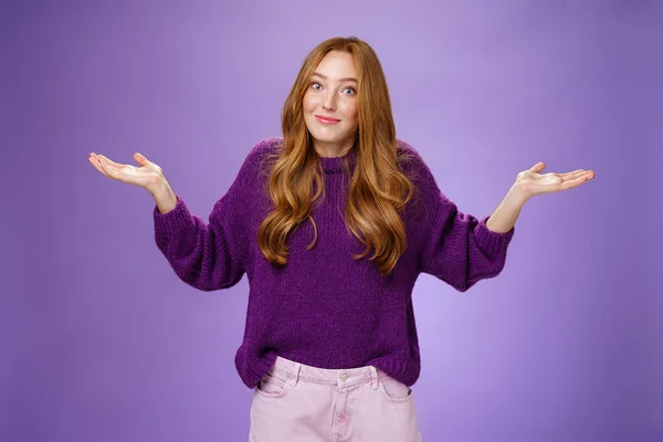 Bem, quem se importa, nada a fazer. Retrato de engraçado e descuidado sem incomodado frio ruiva feminino encolhendo com as mãos estendidas e sorriso apertado sendo inconsciente e não dando interesse sobre fundo roxo — Fotografia de Stock