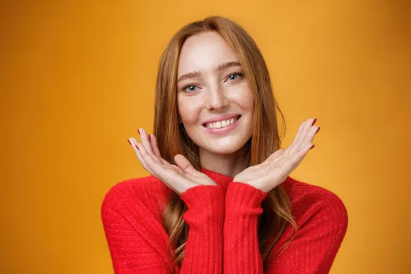 Close-up tiro de sensual tenra e gentil menina gengibre com romance e olhar feliz segurando palmas perto de pele limpa pura com sardas sorrindo alegremente inclinando a cabeça olhando amigável sobre a parede laranja — Fotografia de Stock