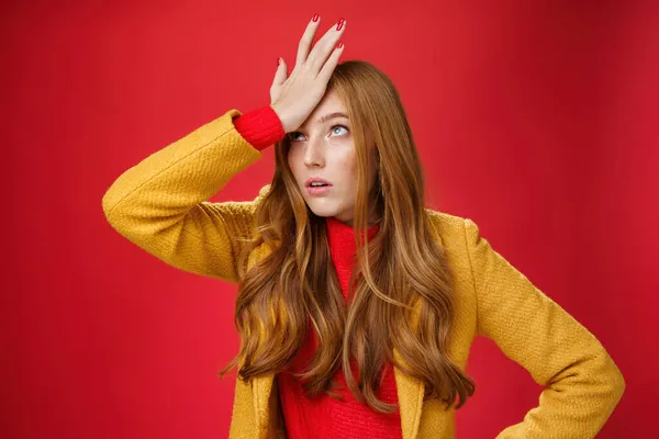 Redhead businesswoman making facepalm gesture with hand on forehead rolling eyes up from annoyance and irritation as being shocked with how dumb client is sighing bothered over red wall, tired — ストック写真