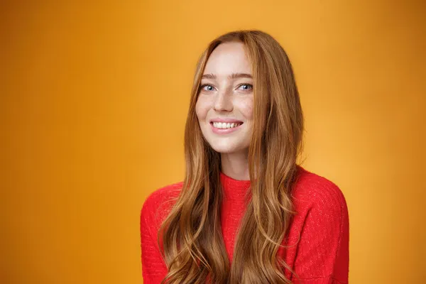 stock image Close-up shot of happy charismatic and carefree cute redhead girl in red knittes outfit smiling joyfully as turning at camera satisfied and joyful posing delighted over orange background