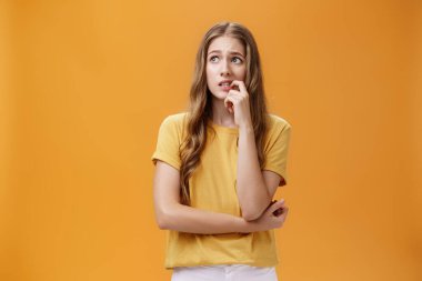 Endişeli, aptal ve kendine güveni olmayan, uzun dalgalı sarı saçlı, gergin, gergin parmaklarını ısıran endişeli ve panik halinde soluna bakan, sorunlu ifadesiyle kaşlarını çatan genç bir kız öğrenci.