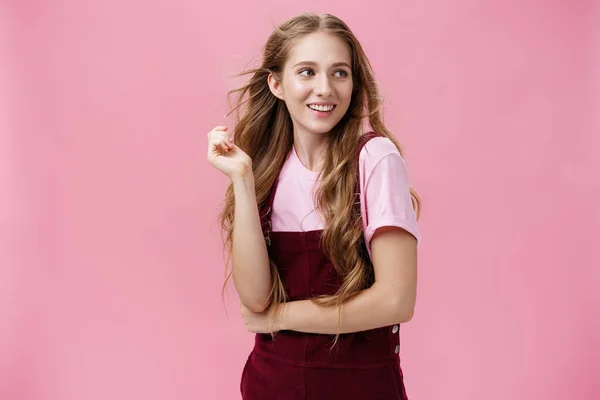 Menina olhando como começar a partir de revistas glamour posando sobre fundo rosa feminino e sensual olhando para a direita com flerte sorriso brincando com o cabelo, enquanto fios cintilando no ar — Fotografia de Stock