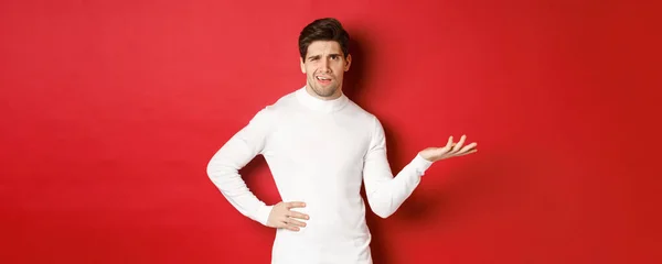 Portrait of confused and displeased man, complaining about something, looking with dismay, standing over red background — Stock Photo, Image