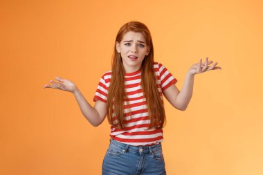 Dikkatsiz, küstah, zengin, zengin bir kız ne der, insanların ne düşündüğünü umursamadan, cahil görün, ellerini yana aç, ilgisiz, umursamadan, turuncu arka planda dur.