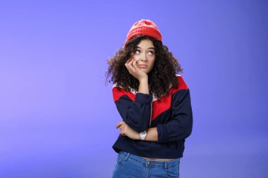 Hayal kırıklığına uğramış ve sıkılmış, kışlık şapkalı, göğsünde el ele tutuşmuş, başını avuç içine yaslamış, sağ üst köşede aptal ve kasvetli görünen, can sıkıntısı hisseden yalnız bir kız portresi.