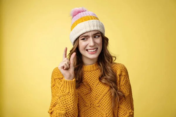 Displeased attractive picky woman describing small object show tiny thing cringing dislike disappointment look upset fingers, describing little salary new job, standing yellow background awkward — Stock Photo, Image