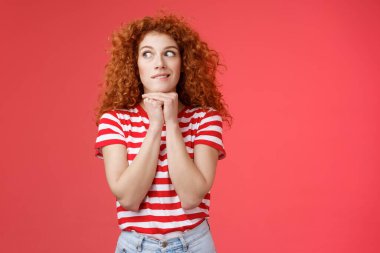 Neşeli, entrika dolu, kızıl saçlı, gülümseyen, kıvırcık saçlı, el ele tutuşmuş, çene yüz hatları çizen, lezzetli hamburgerleri düşünen kırmızı arka planı ısıran bir kadın.