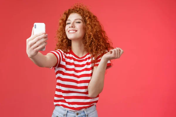 Bonito satisfeito feliz boa aparência ruiva ruiva menina encaracolado penteado sorrindo perfeito sorriso posando encantado divertido segurar smartphone tendo selfie gravar mensagem de vídeo delicadamente vermelho fundo — Fotografia de Stock