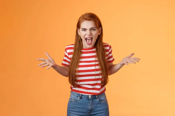 Pissed angry and annoyed redhead female arguing yelling with hatred and anger, spread hands sideways dismay, complain look disappointed upset and hateful, stand orange background — стоковое фото