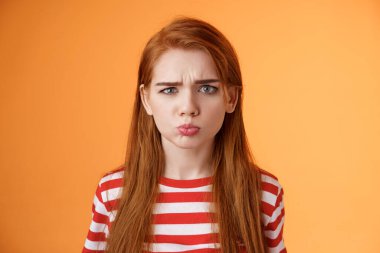 Çocukça davranışlar sergileyen, somurtan, somurtan, suratını asan, haksız durumdan şikayet eden, mızmızlanan, suratını buruşturan, çocukça bir istek duyan, fotokopi alanı turuncu arka plan satın alan, çocuksu bir kız.