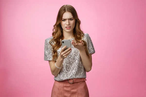 Frustrated pissed woman keep receiving strange messages cringing grimacing bothered look smartphone display gesturing irritated confused, cannot understand article, pink background — Stock fotografie