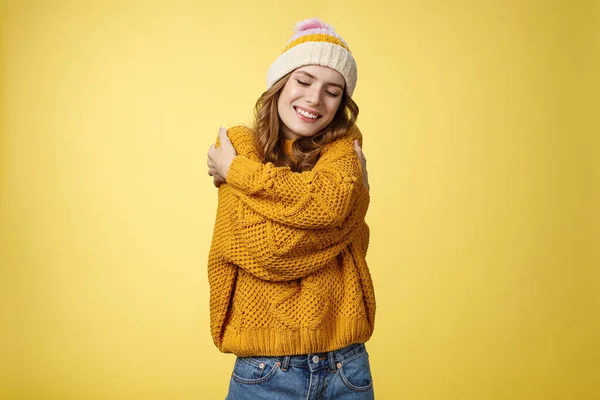 Tenderness, happiness wellbeing concept. Charming feminine cute stylish girl liking new warm sweater hugging embracing herself close eyes dreamy smiling feeling romantic coziness yellow background — Stock Photo, Image