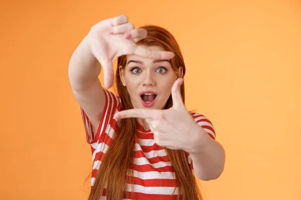 Kreatywna rudowłosa studentka czerwieni zainspirowała się, obrazując, jak uchwycić ciekawe ujęcie, wydłużyć ramiona pokazać gestem ramki patrzeć przez ręce zdumiony, otwarte usta dysząc entuzjastycznie — Zdjęcie stockowe
