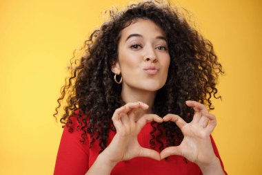 Aşk ve romantizmi ifade eden, hayranlık ya da sempati ile itiraf eden kıvırcık saçlı, dudaklarını öpücükle kıvırcık dudaklı romantik ve hassas bir genç kız arkadaşın yakın plan çekimi.