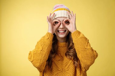 Kadife şapkalı, kadife şapkalı, geniş gözlü, neşeli, çekici genç Avrupalı kadın dürbünlü gözlüklerin parmaklarını yaptığını, şaşkın bir şekilde gülümsediğini, sarı arka plan çizdiğini gördü.