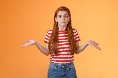 Sorgusuz, cahil, sevimli, modern, stil sahibi, kızıl saçlı kadın ellerini yan yana uzatıyordu. Bilinci yerinde değildi, kafası karışıktı, zor bir soruydu, cevabı yoktu, turuncu arka planda duruyordu.