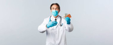 Covid-19, virüsü önleme, sağlık çalışanları ve aşı konsepti. Tıbbi maske takan heyecanlı ve şok olmuş doktor yeni ilaçlara tepki veriyor.