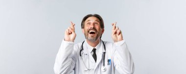 Covid-19, virüsü önleme, sağlık çalışanları ve aşı konsepti. İyimser, umutlu, beyaz önlüklü, şans dileyen, gülümseyen, dilek tutan doktorların yakın çekimi.