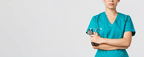 Covid-19, choroba koronawirusowa, koncepcja pracowników służby zdrowia. Zbliżenie pewnego siebie lekarza azjatyckiego, lekarza w kitlu medycznym, oznaczanie krzyżowych ramion i trzymanie stetoskopu, białe tło — Zdjęcie stockowe