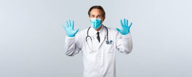 Covid-19, virüsü önleme, sağlık çalışanları ve aşı konsepti. Beyaz önlüklü, tıbbi maskeli ve eldivenli heyecanlı erkek doktor.